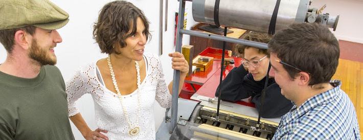 Professor talking to students next to a printing press
